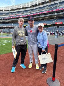 Baseball player with two women at a stadium, smiling and holding bags.