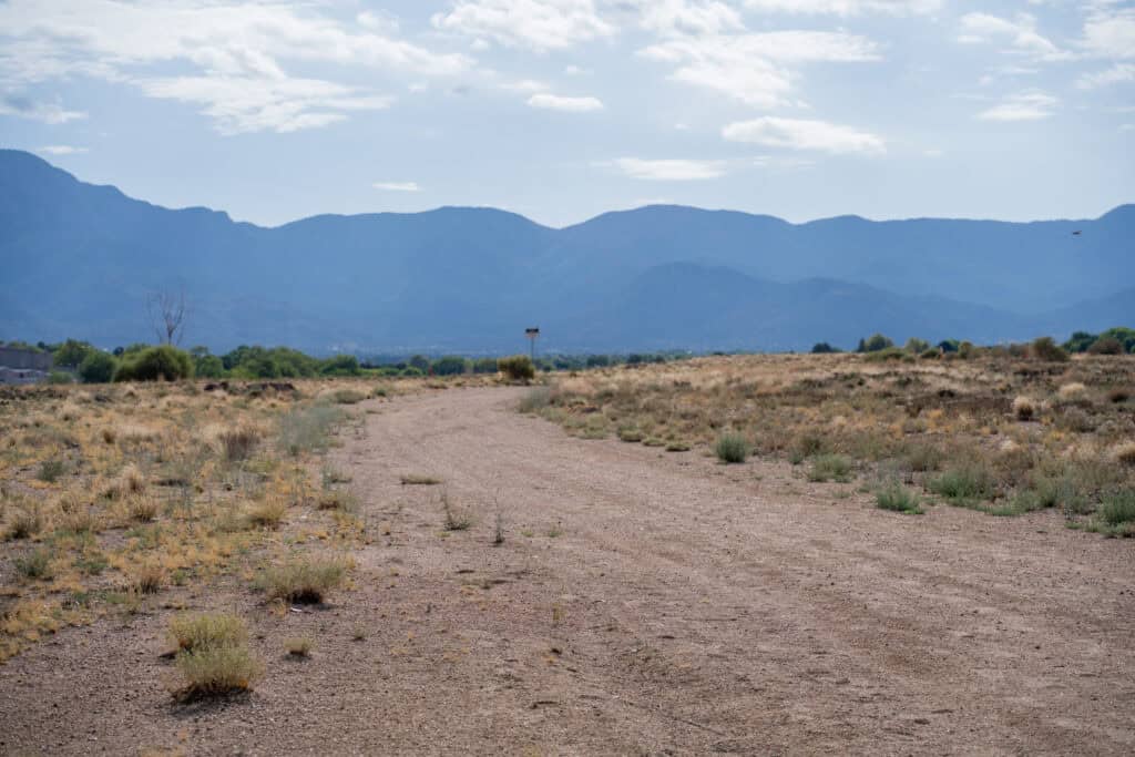 Desert landscape with mountain range in the background and a dirt path in the foreground.