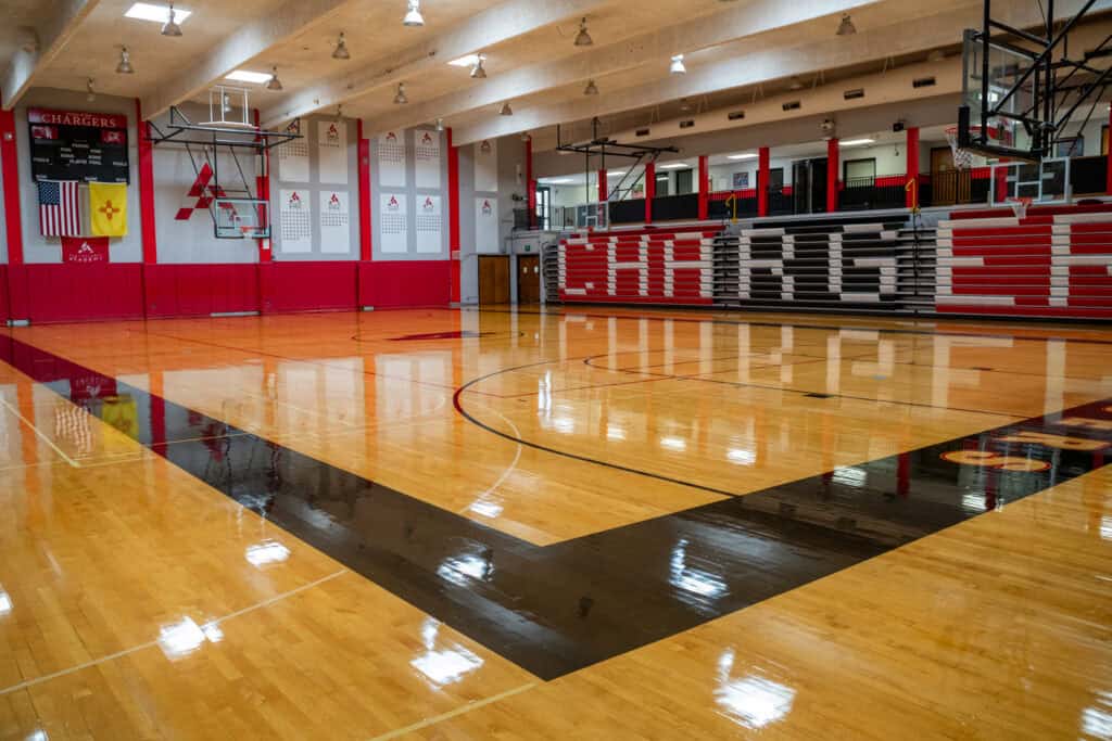 Indoor basketball court at Albuquerque Academy with polished wood floor and team banners.