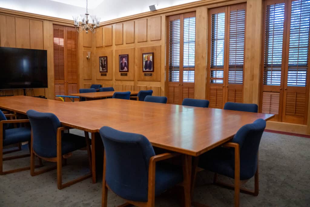 Albuquerque Academy conference room with wooden walls and blue chairs around a large table.