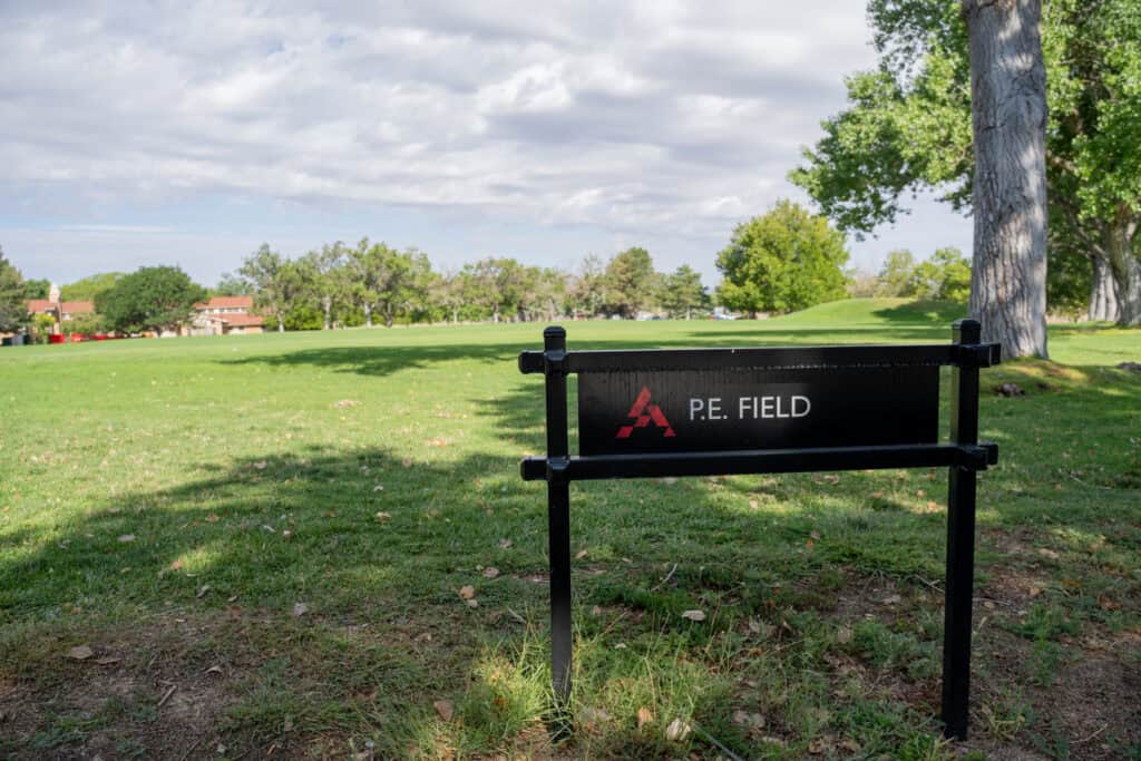 Albuquerque Academy P.E. Field with green grass and trees under cloudy sky.