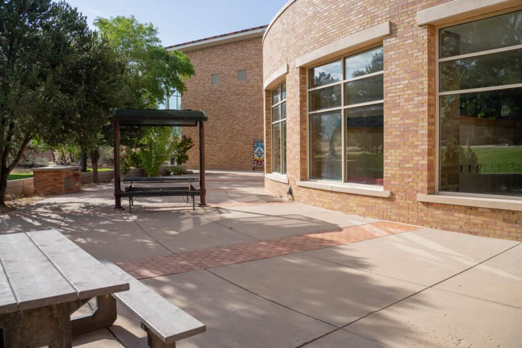 Albuquerque Academy campus with brick building, large windows, and outdoor seating area.