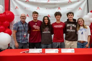 Group of students and coach at Albuquerque Academy signing event with Harvard and Brown University.