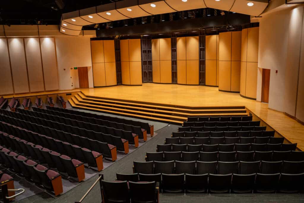 Empty auditorium stage at Albuquerque Academy with seating and wooden panels.