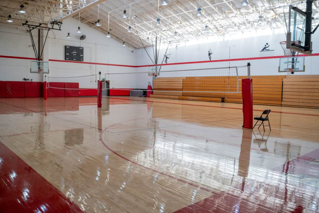 Indoor gymnasium at Albuquerque Academy with polished wooden floor and volleyball net.