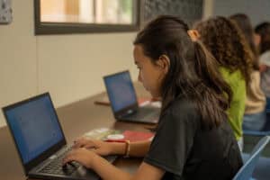 Student typing on laptop in a classroom