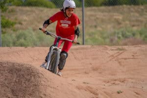 Young cyclist rides over a dirt track berm